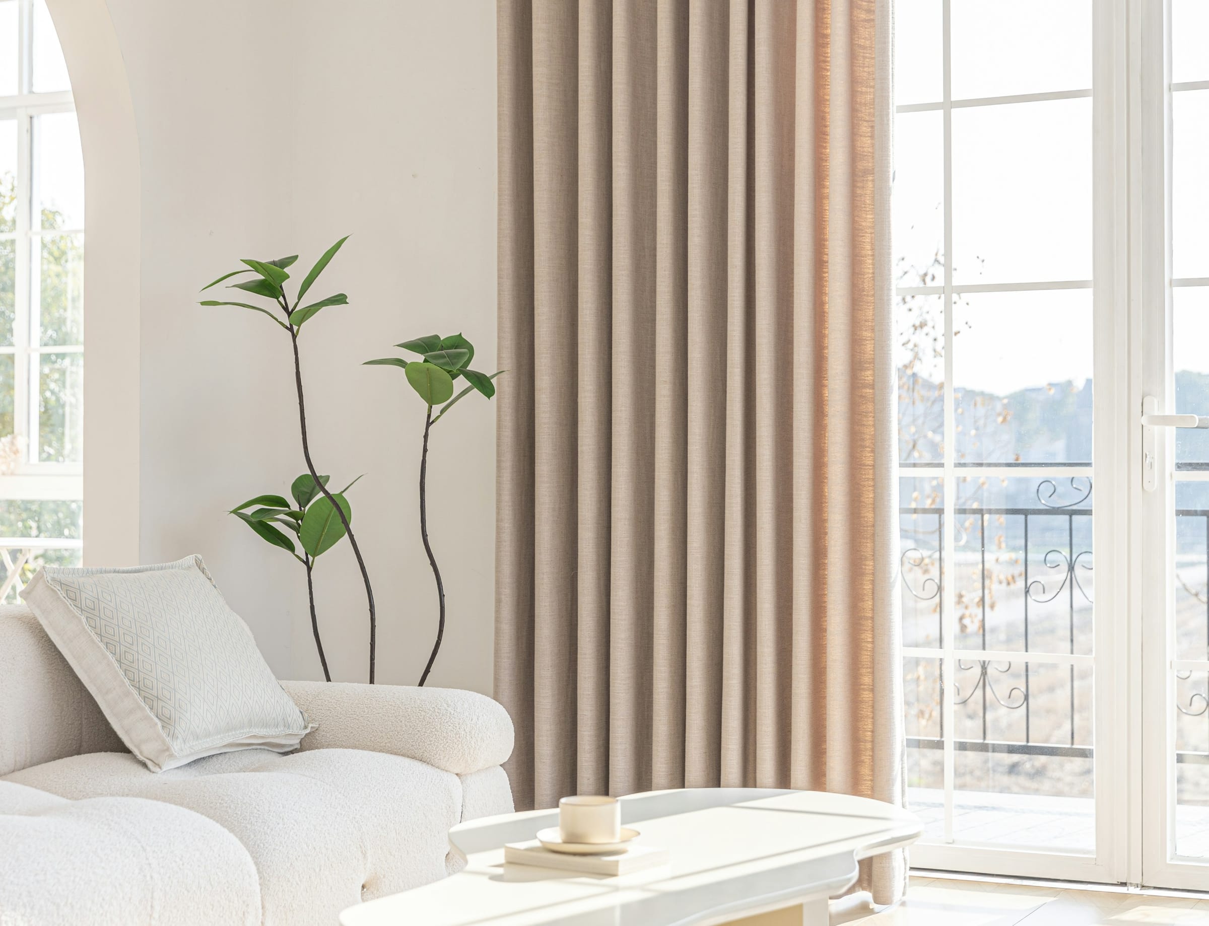 A serene, light-filled lounge with a cream wall, bouclé sofa and linen drapes.
